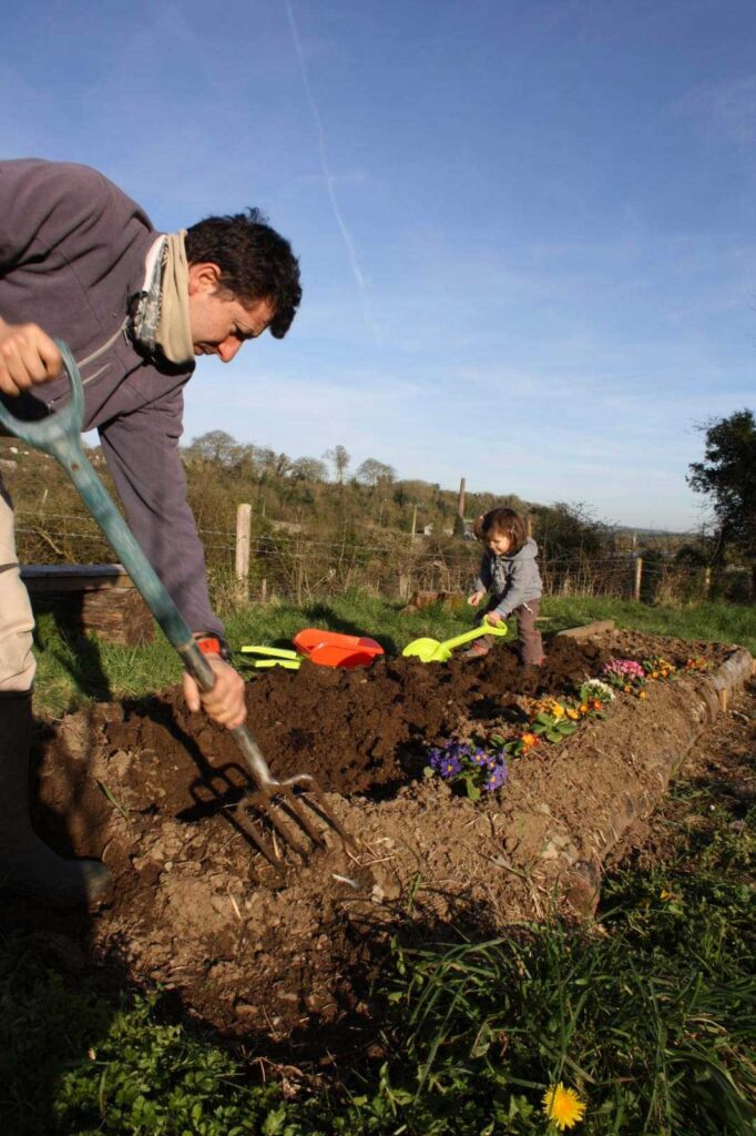Luciano Diez doing garden work with a child trying to help with plastic tools