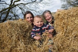 Baby being held between 2 hay bales